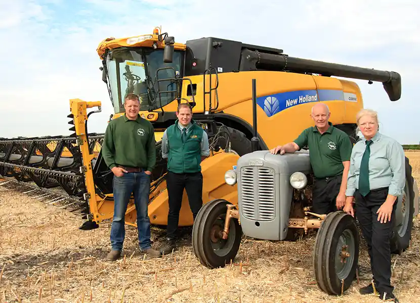 The Webster family — four generations of Lancashire farmers — standing together at harvest time beside a combine harvester